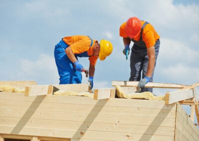 Two construction carpenters roofers workers installing wood board roof